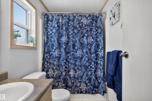 Window with wood trim, built-in vanity with integrated sink, toilet, and shower with curtain rod - 1405 53222 Range Road 272, Rural Parkland County, AB 