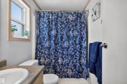 Window with wood trim, built-in vanity with integrated sink, toilet, and shower with curtain rod - 