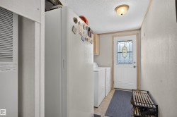 Entryway with wood-finish flooring, white paneled walls, and a white exterior door with decorative glass inlay - 