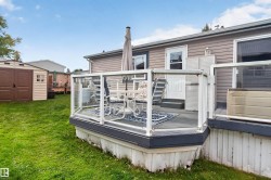 Outdoor deck with glass panel railing and composite decking, featuring a white exterior door, and vinyl siding - 