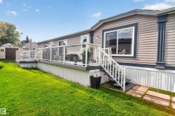 Expansive exterior deck with glass panel railings and white balustrade stairs, featuring composite decking - 