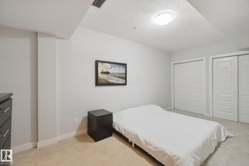 Recessed ceiling with flush mount lighting, neutral tone carpeting, two double-door closets, and a built-in chest of drawers with a dark countertop - #125 5151 Windermere Bv Sw Sw, Edmonton, AB 