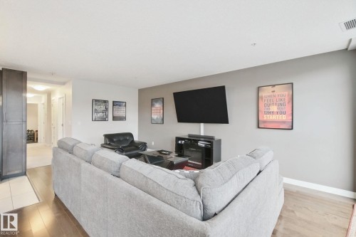 Wood-finish flooring, accent wall, built-in cabinetry, recessed lighting, ceiling-mounted television - #125 5151 Windermere Bv Sw Sw, Edmonton, AB 