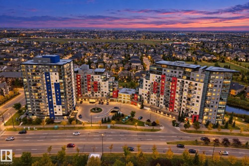 Modern high-rise architecture featuring multiple residential towers, a circular drive with landscape planting, and integrated street-level lighting - #125 5151 Windermere Bv Sw Sw, Edmonton, AB 