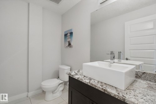 Vanity featuring a rectangular vessel sink, polished chrome faucet, and stone countertop - #125 5151 Windermere Bv Sw Sw, Edmonton, AB 