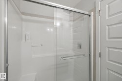 Sliding glass shower enclosure with a white acrylic surround, integrated shelving, and a polished chrome shower fixture - 