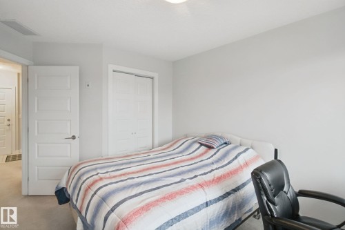 Neutral wall paint, ceiling light fixture, white interior door with brushed nickel hardware, and bi-fold closet doors - #125 5151 Windermere Bv Sw Sw, Edmonton, AB 