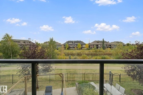 Glass panel railing and black metal posts on a balcony overlooking a fenced yard - #125 5151 Windermere Bv Sw Sw, Edmonton, AB 