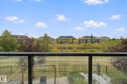 Glass panel railing and black metal posts on a balcony overlooking a fenced yard - 