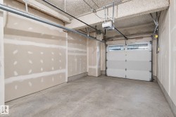 Garage space featuring a concrete floor, exposed ceiling, and an overhead garage door with upper window panels - 