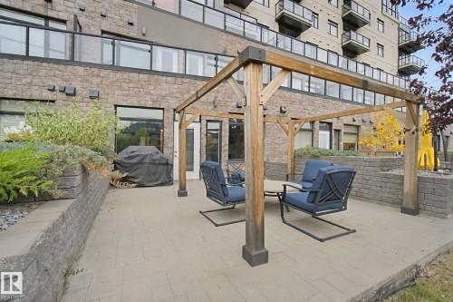 Expansive patio featuring a wood pergola, paver flooring, and integrated stone retaining walls - #125 5151 Windermere Bv Sw Sw, Edmonton, AB 