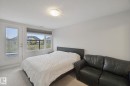White walls with overhead flush-mount lighting, large window with roller shade, and light-toned carpet flooring - #125 5151 Windermere Bv Sw Sw, Edmonton, AB 