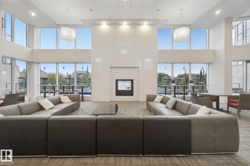 Two-story window wall, built-in fireplace, recessed ceiling lighting, two decorative pendant lights, and carpet flooring - #125 5151 Windermere Bv Sw Sw, Edmonton, AB 