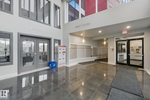 Spacious lobby featuring polished stone flooring, high ceilings, large windows, and contemporary lighting - #125 5151 Windermere Bv Sw Sw, Edmonton, AB 
