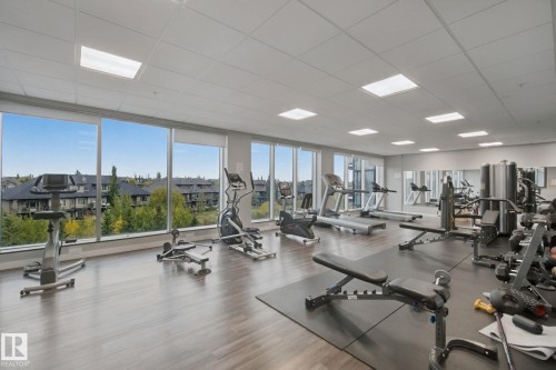 Integrated fitness center featuring extensive window-line, wood-finish flooring, recessed lighting, and wall-mounted mirrors - #125 5151 Windermere Bv Sw Sw, Edmonton, AB 