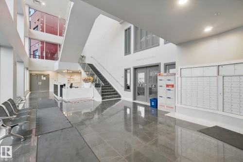 Expansive lobby with high ceilings, polished tile flooring, a reception desk, and a multi-story window wall - #125 5151 Windermere Bv Sw Sw, Edmonton, AB 