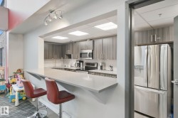 Kitchenette featuring a pass-through counter, stainless steel appliances, recessed ceiling lights, track lighting, and wood-finish cabinetry - 