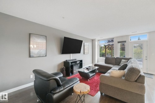 Hardwood-finish flooring, light grey wall paint, and large windows with transom panels - #125 5151 Windermere Bv Sw Sw, Edmonton, AB 