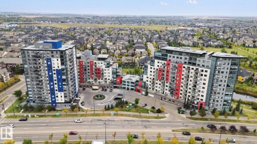 Modern multi-story buildings featuring balconies, a circular drive, and an underground parking entrance - #125 5151 Windermere Bv Sw Sw, Edmonton, AB 