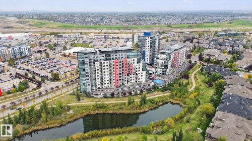 Modern multi-story buildings, expansive surface parking, paved roadways, and surrounding residential properties - #125 5151 Windermere Bv Sw Sw, Edmonton, AB 