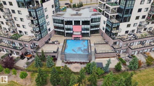 Two multi-story buildings with balconies, a central courtyard, and a rectangular pool - #125 5151 Windermere Bv Sw Sw, Edmonton, AB 