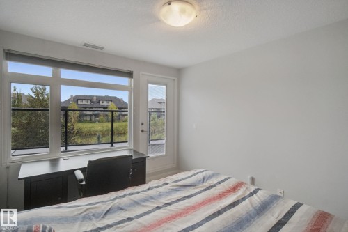 White walls featuring a large multi-pane window and an exterior door with a glass panel - #125 5151 Windermere Bv Sw Sw, Edmonton, AB 