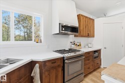 Stainless steel range with a coordinating microwave, white subway tile backsplash, wood-finish cabinetry, white countertops, and a double basin sink - 