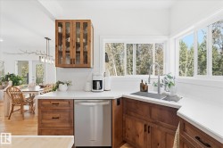 Kitchen featuring wood cabinetry, white countertops, stainless steel dishwasher, undermount sink with a gooseneck faucet, and a subway tile backsplash - 