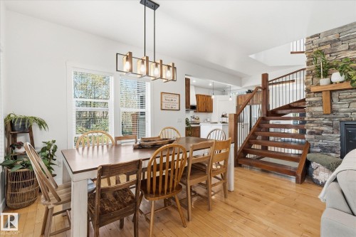 Hardwood flooring throughout, stone-clad fireplace, open-tread wood staircase with metal balusters, contemporary linear chandelier, and multiple windows with natural light - #45 53122 Rge Road 14, Rural Parkland County, AB 