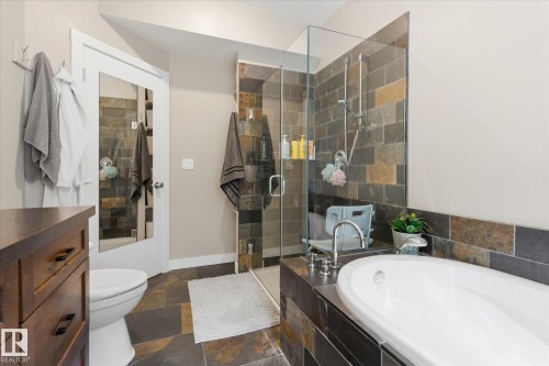Walk-in shower with glass enclosure, freestanding soaking tub, and natural stone-look tile flooring - #45 53122 Rge Road 14, Rural Parkland County, AB 