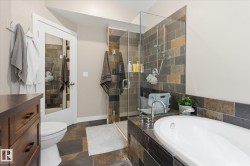 Walk-in shower with glass enclosure, freestanding soaking tub, and natural stone-look tile flooring - 