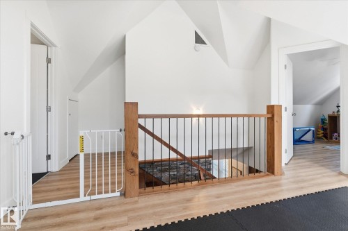 Wood-finish flooring, white walls, wood newel posts, and black metal balusters - #45 53122 Rge Road 14, Rural Parkland County, AB 