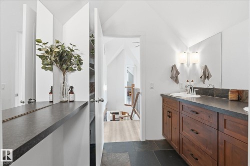 Custom wood-finish vanity with an integrated sink, dark countertop, and sconce lighting - #45 53122 Rge Road 14, Rural Parkland County, AB 