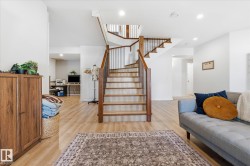 Wood-finish flooring throughout, featuring a multi-level staircase with wood treads and metal balusters - 
