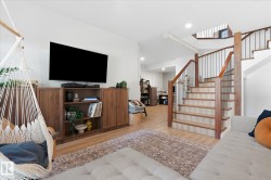 Staircase with wood treads and metal balusters, wood-finish flooring, built-in shelving, recessed lighting, and white walls - 