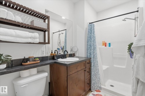 Built-in open shelving, dark wood-finish vanity with drawer storage, integrated sink, dark countertop, and stand-up shower with a dark finish shower rod - #45 53122 Rge Road 14, Rural Parkland County, AB 