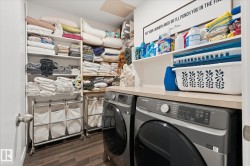 Built-in shelving, wood-finish flooring, light-toned countertop, and integrated washer and dryer - 