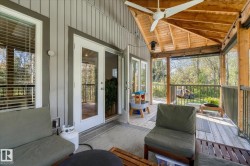 Covered deck with a wood-plank ceiling, exposed wood beams, and a ceiling fan - 