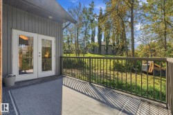 Outdoor deck with dark railing, white French doors, and gray vertical siding - 