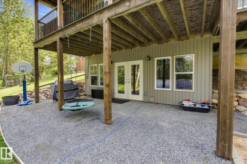 Expansive covered patio with wooden beam construction and gravel flooring, offering sheltered outdoor entertaining space - #45 53122 Rge Road 14, Rural Parkland County, AB 