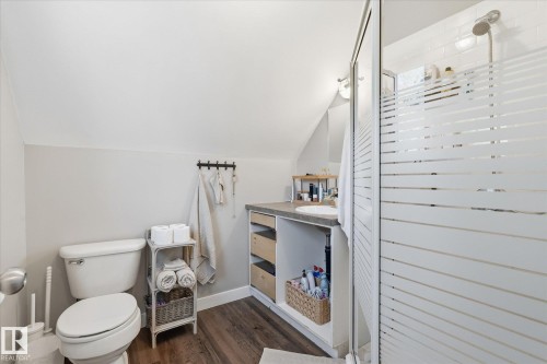 Shower with frosted glass enclosure, single vanity with integrated sink, wood-finish flooring, and sloped ceiling - #45 53122 Rge Road 14, Rural Parkland County, AB 
