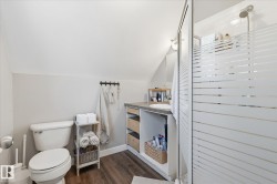 Shower with frosted glass enclosure, single vanity with integrated sink, wood-finish flooring, and sloped ceiling - 