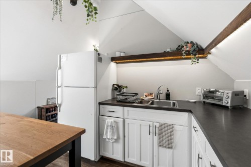 Kitchenette with vaulted ceilings, white cabinetry, dark countertops, and a stainless steel sink - #45 53122 Rge Road 14, Rural Parkland County, AB 