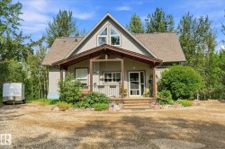 A-frame style residence featuring a covered porch with exposed beams, wood stairs, and a gravel driveway - 