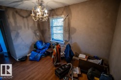 Wood-finish flooring with a decorative chandelier, a window, and textured wall finishes - 