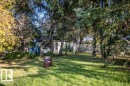 Mature tree-lined grounds with expansive lawn and established shade canopy - 219 Second Avenue, Duvernay, AB 