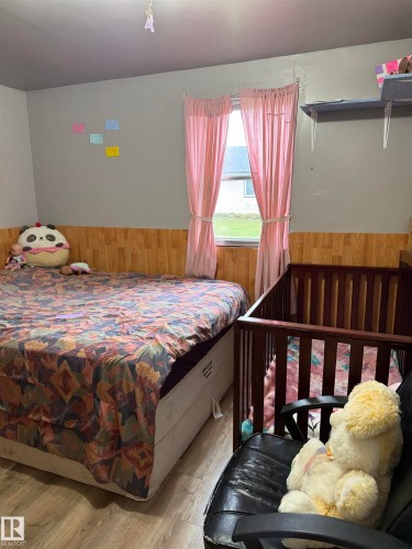 Wood-finish flooring with a neutral wall color and wood-look paneling - 4626 51 Avenue, Willingdon, AB 