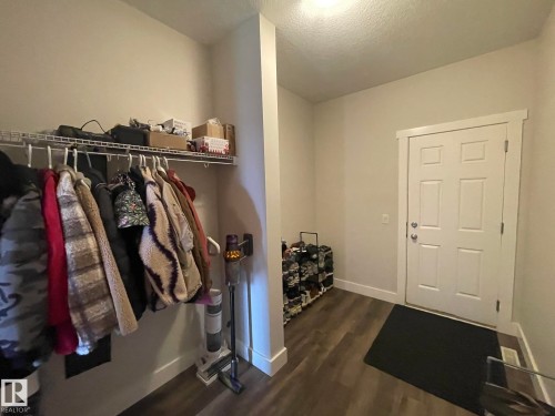 Entryway featuring wood-finish flooring, a paneled door with white trim, and a built-in wire shelf with hanging rod - 7939 Erasmus Crescent Nw, Edmonton, AB 