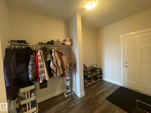 Entryway with wood-finish flooring, a six-panel door, and a built-in wire shelf and rod system - 7939 Erasmus Crescent Nw, Edmonton, AB 