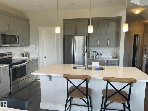 Kitchen featuring gray cabinetry, stainless steel appliances, white subway tile backsplash, white countertops, and wood-finish flooring - 7939 Erasmus Crescent Nw, Edmonton, AB 